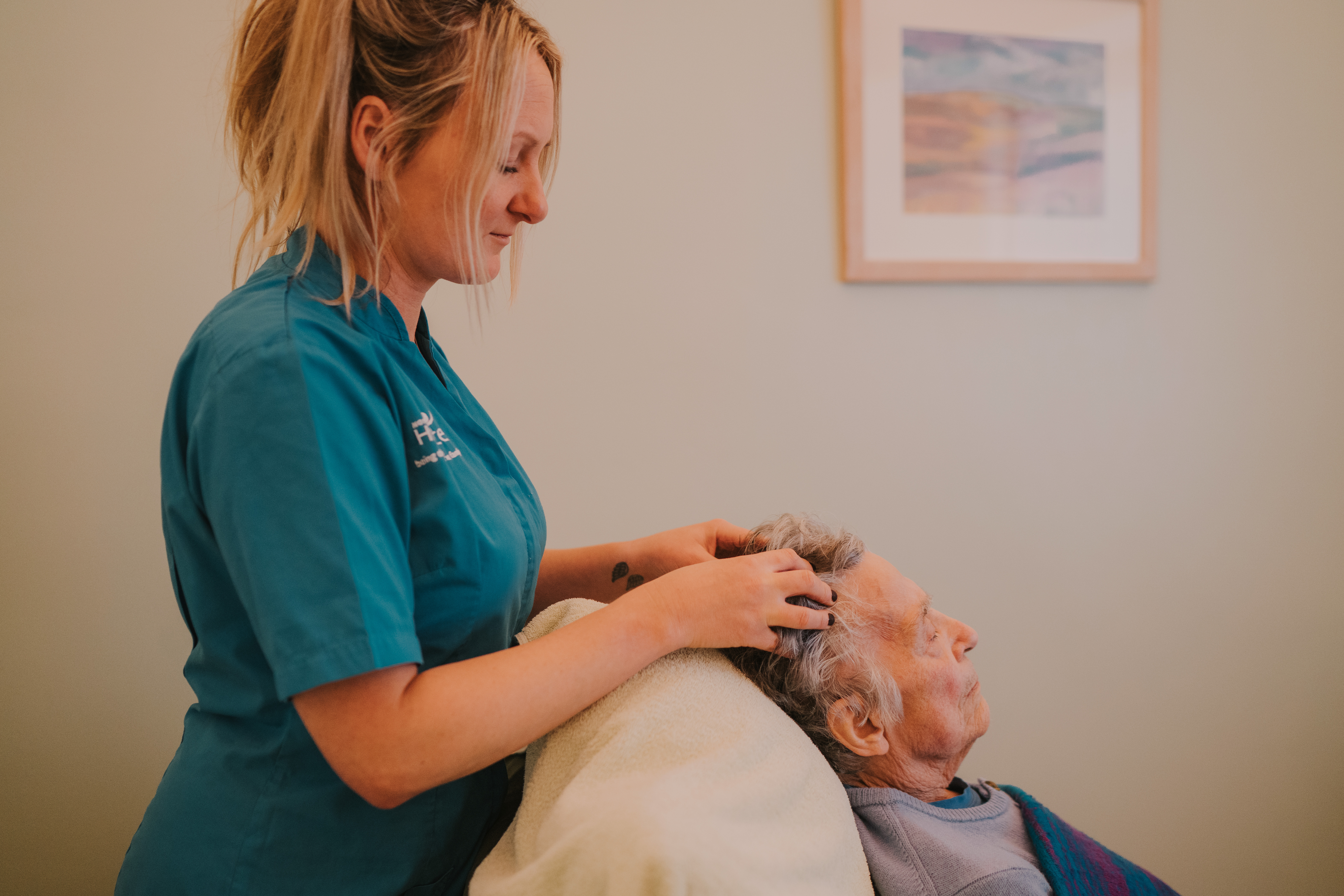 Female complementary therapist performing reiki on a female patient by touching her head